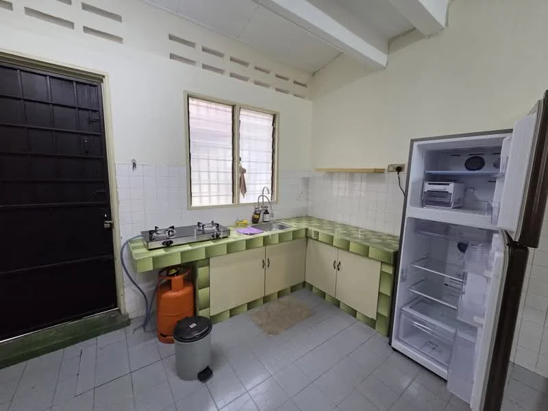Kitchen features: green patterned countertop, single-bowl stainless-steel sink, chrome pull-down faucet, 2-burner gas hob, built-in refrigerator, freestanding gas cylinder, grey tiled flooring, white tiled walls, wooden cabinetry, window with grid pattern, door with black paneling.