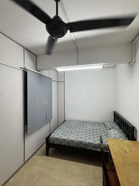 Bedroom features: queen-size bed with grey geometric patterned bedding, black wooden bed frame, ceiling fan, built-in wardrobe with sliding doors, light-colored walls, tile flooring, wooden table, window with grey curtain; style: minimalist.