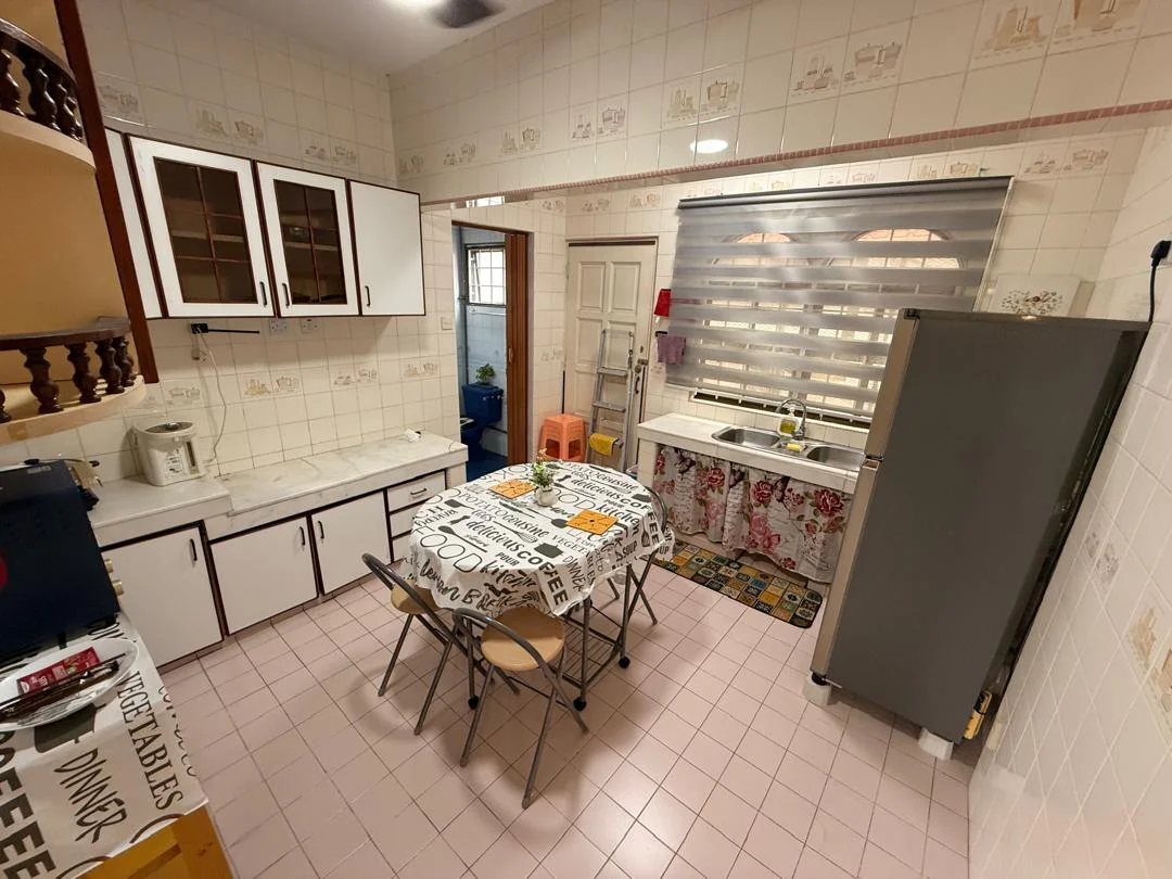 Kitchen features: white tiled walls with decorative patterns, light pink tiled flooring, white cabinetry with black handles, marble countertop, stainless-steel fridge, kitchen table with printed tablecloth, four folding chairs, window with horizontal blinds, sink with faucet, decorative potted plant on countertop; style: traditional.