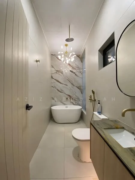 Bathroom features: freestanding bathtub, one-piece toilet, single-sink vanity with wood cabinet, gold faucet, marble wall cladding, recessed ceiling lights, chandelier, mirror with rounded edges, grey countertop, wall-mounted soap dispenser, window with black frame; style: modern.