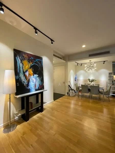 Living features: wooden flooring, white painted walls, track lighting, floor lamp, abstract artwork on wall, dining table with chairs, chandelier, decorative vase with flowers, open shelving unit, neutral color palette; style: modern.