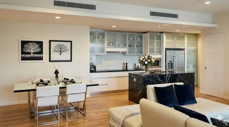 Kitchen features: white cabinetry with glass upper cabinets, black marble countertop, stainless-steel fridge, built-in oven, 4-burner gas hob, chrome pull-down faucet, single-bowl stainless-steel sink, recessed downlights, open shelving, wooden flooring; style: modern. Dining features: 6-seater glass dining table, metal dining chairs, decorative vase with flowers, framed artwork on walls; style: modern. Living features: cream fabric sofa, decorative cushions, coffee table, area rug, wall-mounted artwork; style: modern.