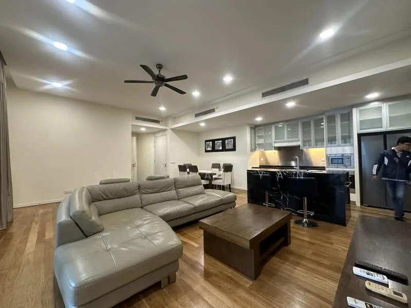 Living features: 3-seater leather sofa in light grey, wooden coffee table, ceiling fan with light, recessed downlights, wooden flooring, open layout to kitchen, wall-mounted TV, dining area visible in background; style: modern. Kitchen features: black granite countertop, stainless-steel appliances, built-in oven, microwave, kitchen island with bar stools, glass-front upper cabinets, ceramic tile backsplash; style: modern.