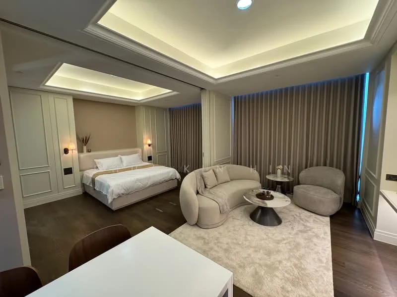Living features: sofa in light beige fabric, coffee table with dark wood finish, area rug in cream color, floor-to-ceiling windows with sheer curtains, recessed downlights, wall-mounted TV, decorative wall paneling, wooden flooring; style: modern. Bedroom features: king-size bed with white bedding, upholstered headboard, built-in wardrobe with sliding doors, recessed ceiling with lighting, wall-mounted bedside lamps, decorative wall paneling, wooden flooring; style: modern.