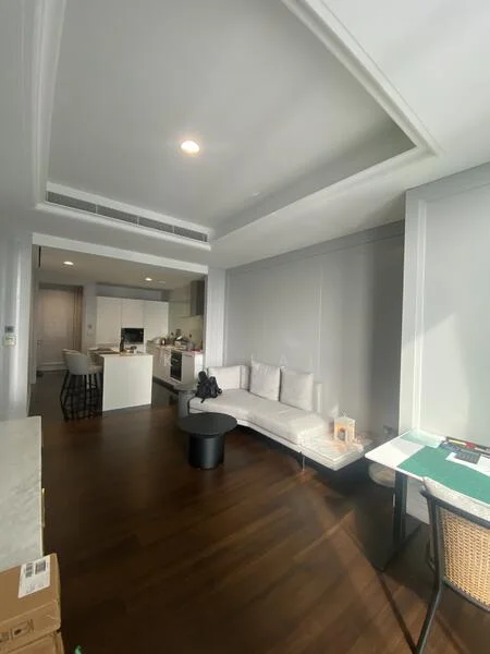 Living features: white sectional sofa, black round coffee table, wood flooring, recessed ceiling lights, large windows with sheer curtains, open layout to kitchen, decorative wall paneling, neutral color scheme; style: modern. Kitchen features: white cabinetry, stainless-steel appliances, marble countertop, bar stools, open shelving, built-in oven, cooktop, dishwasher; style: modern.