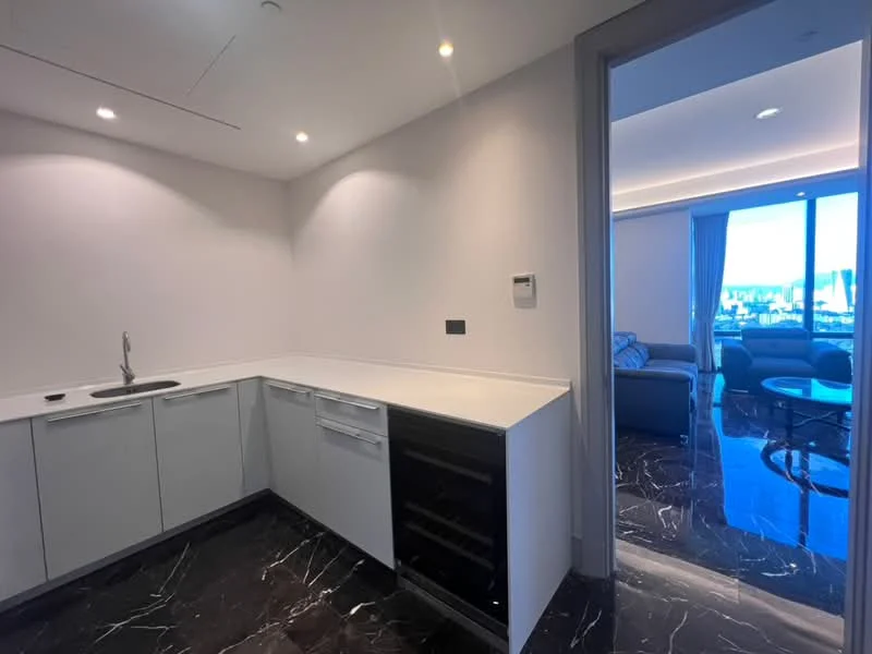 Kitchen features: white cabinetry, black marble countertop, stainless-steel sink, chrome faucet, built-in dishwasher, wine cooler, recessed downlights, black marble flooring, open layout to living area, floor-to-ceiling windows, city view; style: modern; view: city.