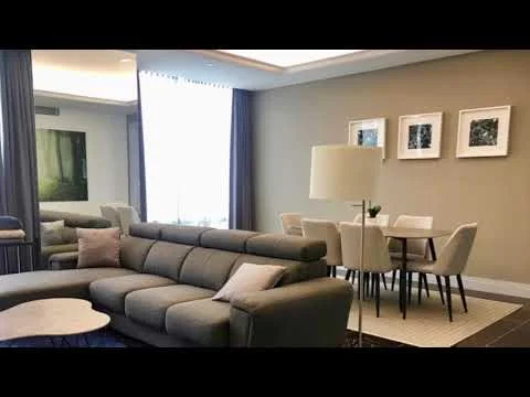 Living features: L-shape sectional sofa in grey, round coffee table, area rug with geometric pattern, floor-to-ceiling windows, sheer curtains, dining table for 6 with upholstered chairs, framed artwork on walls, recessed ceiling lights, wall-mounted mirror; style: modern.