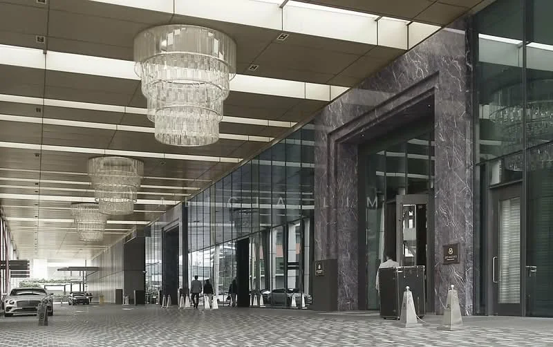 Exterior type: high-rise condominium; features: glass curtain wall, marble facade, chandeliers in entrance, double-volume main lobby, paved walkway, security barriers at entrance; style: modern.