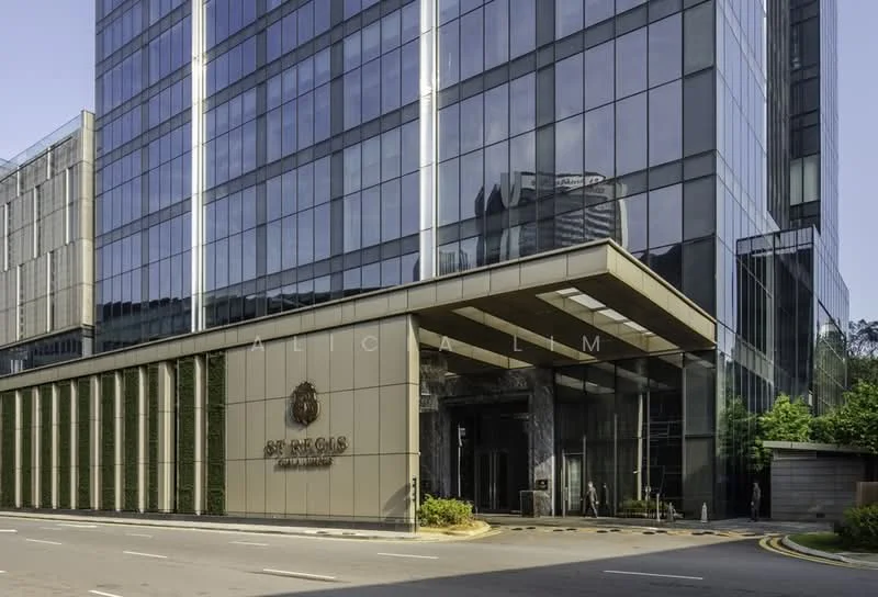 Exterior type: high-rise condominium; features: glass curtain wall, cream painted facade, recessed balconies, feature lighting at night, double-volume main lobby, landscaped entrance with greenery, paved driveway, signage at entrance; style: modern.