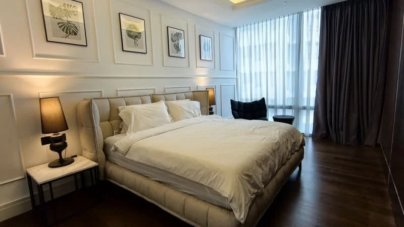 Bedroom features: king-size bed with upholstered headboard, white bedding, 2 bedside tables with lamps, black accent chair, floor-to-ceiling windows, sheer curtains, dark curtains, wooden flooring, decorative wall panels, framed artwork on walls, recessed ceiling lights; style: modern.