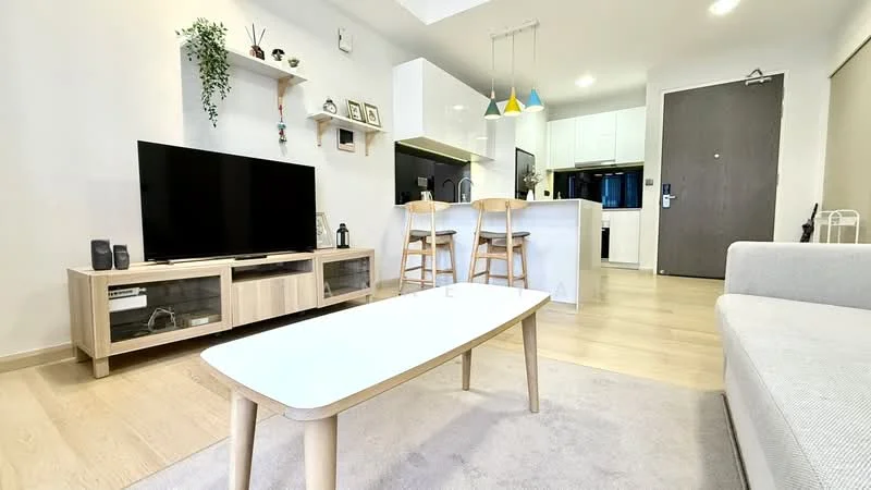Living features: light wood flooring, white painted walls, ceiling with recessed lighting, wall-mounted TV, wooden TV console, coffee table with white top and wooden legs, beige area rug, sofa in light grey fabric, bar stools at kitchen counter, pendant lights in multiple colors, open-plan layout connecting to kitchen, decorative wall shelf with plants; style: modern.