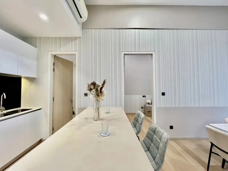 Kitchen features: white cabinetry, light wood countertop, stainless-steel sink, chrome faucet, recessed lighting, open shelving, bar seating with three chairs, light wood flooring, textured wall panels, air conditioning unit; style: modern. Room features: doorway leading to another room, light-colored walls, neutral decor.