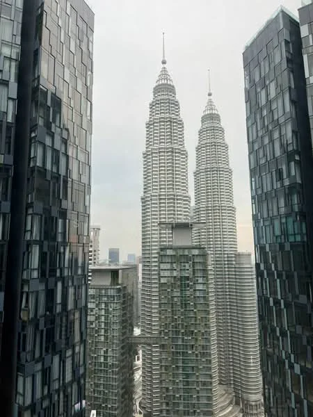 Exterior type: high-rise condominium; features: glass curtain wall, twin towers, surrounded by modern buildings, city skyline view, urban setting, approximately 50-storey high-rise, feature lighting at night; style: modern.