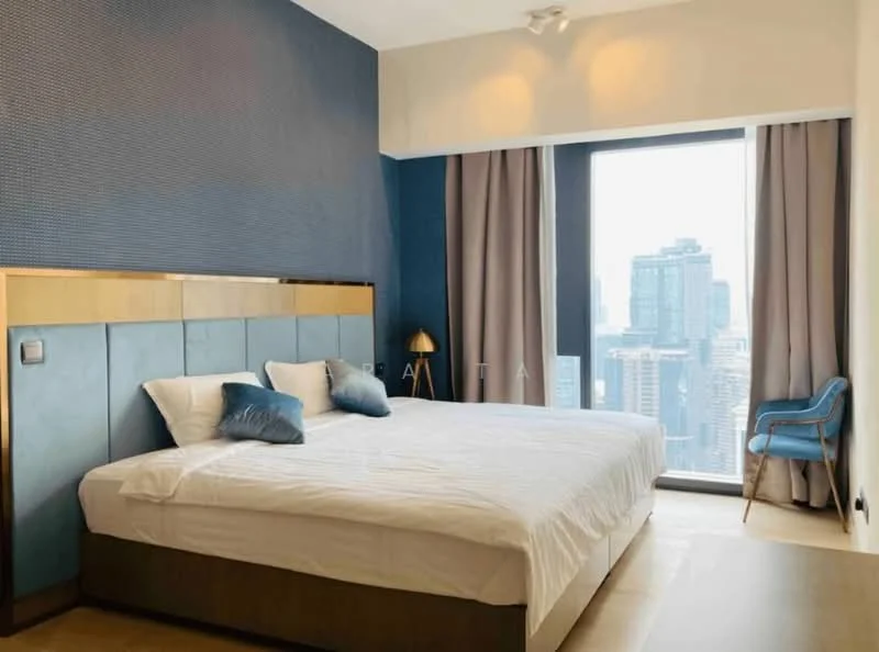 Bedroom features: king-size bed with white bedding, upholstered headboard in blue, two blue decorative pillows, floor-to-ceiling windows, city skyline view, wooden flooring, blue accent wall, curtains in light grey, table lamp on bedside, blue accent chair; style: modern; view: city.