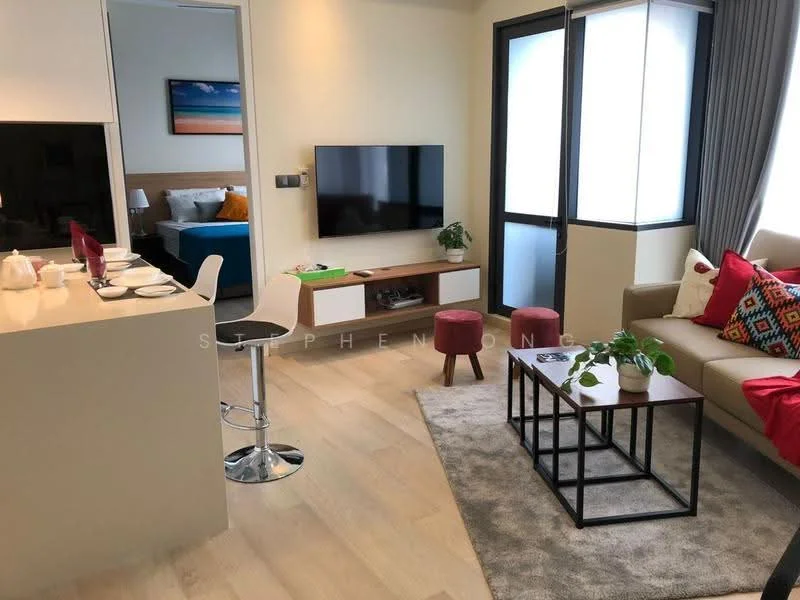 Living features: light wood flooring, cream painted walls, sofa with colorful cushions, coffee table with black frame, area rug with neutral color, wall-mounted TV, TV console with white cabinetry, decorative houseplants, bar stools at kitchen counter, large windows with natural light, grey curtains; style: modern. Room features: bed visible in background, blue bedding.