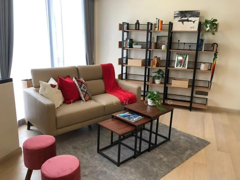 Living features: 3-seater leather sofa in beige, red and black decorative cushions, wooden coffee table with black metal frame, area rug with grey pattern, black metal shelving unit with decorative items, houseplants in ceramic pots, framed artwork on wall, floor-to-ceiling windows with sheer curtains, light wood flooring, two pink upholstered stools; style: modern.