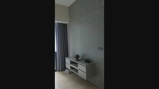Room features: light wood flooring, grey feature wall, built-in cabinetry, TV console, curtains, decorative plant, wall-mounted electrical outlets, neutral wall color; style: modern.
