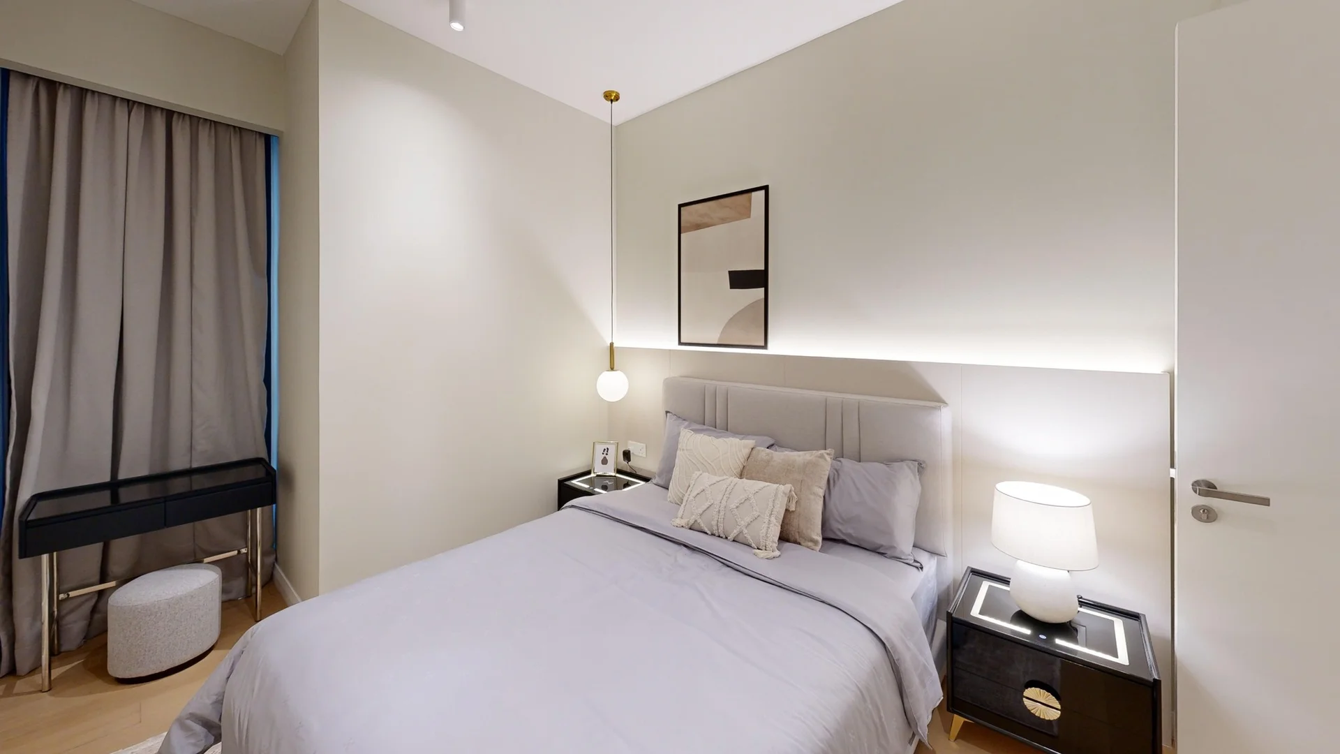 Bedroom features: queen-size bed with grey bedding, upholstered headboard, two bedside tables with lamps, framed artwork on wall, pendant light fixture, curtains in grey fabric, light wood flooring, decorative throw pillows, wall-mounted light above the bed, minimalist decor; style: modern.