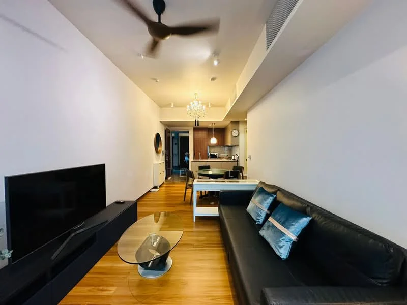 Living features: 3-seater leather sofa in black, glass coffee table, wall-mounted TV, wooden flooring, ceiling fan, chandelier, decorative mirror, area rug, open layout to kitchen, wall with light-colored paint; style: modern. Kitchen features: kitchen island, stainless-steel appliances, wood cabinetry, countertop with bar seating, recessed downlights, open layout to living room; style: modern.
