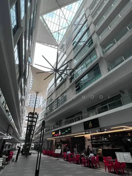 Exterior type: mixed-use development; features: glass curtain wall, open-air atrium, modern architectural design, large skylight, outdoor dining area, decorative ceiling fan, canopy awnings, paved flooring, multiple levels, retail spaces on ground floor, seating area with red chairs; style: contemporary.