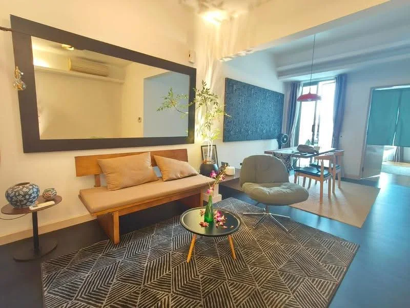 Living features: grey fabric sofa, wooden bench with cushions, round coffee table with black surface, area rug with geometric pattern, large wall mirror, pendant light fixture, decorative plant, dining table with chairs, floor-to-ceiling windows, sliding glass door, wall-mounted air conditioning unit; style: modern.