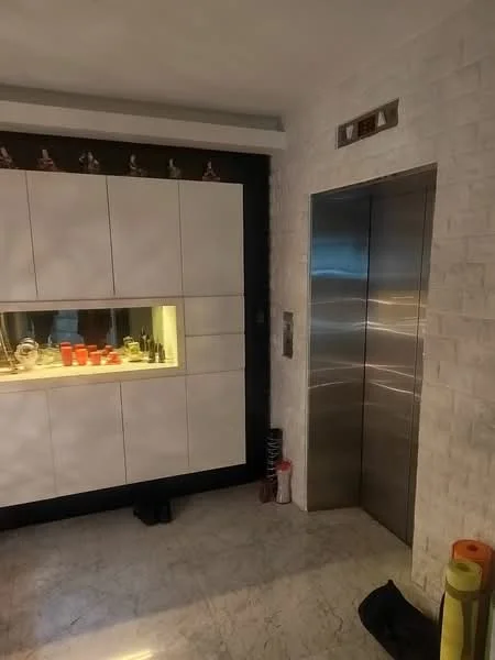 Room features: elevator, white cabinetry, marble flooring, backlit display area, decorative items on shelf, black accent wall, lighting fixtures, floor space with no visible furniture; style: modern.