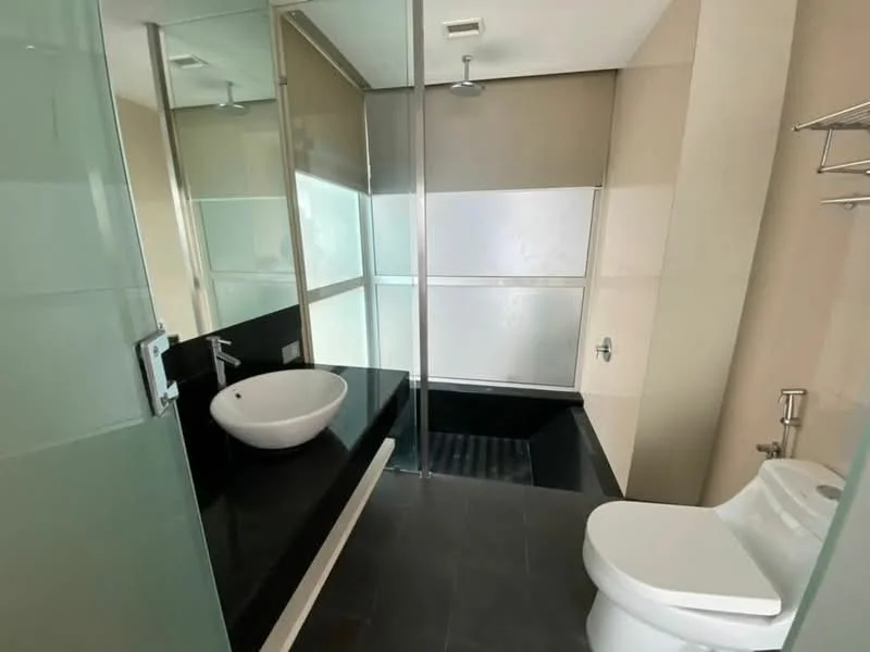 Bathroom features: black granite countertop, white vessel sink, chrome faucet, walk-in shower with glass enclosure, rain shower head, toilet, tile flooring, glass partition, wall-mounted towel rack; style: modern.