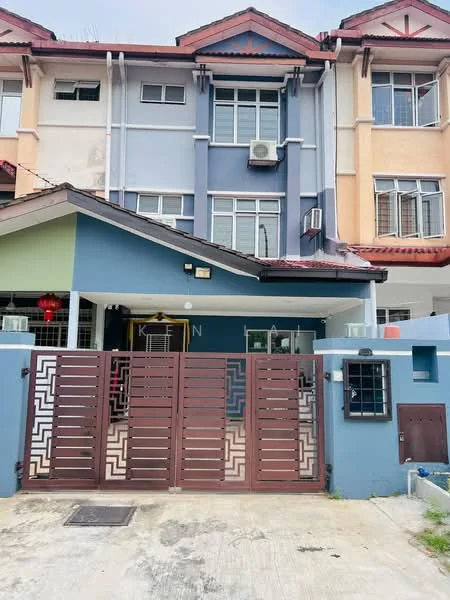 Exterior type: linked terrace house; features: two-storey building, painted facade in blue and cream, brown wooden gate with geometric pattern, air conditioning unit visible, front porch area, windows with grills, decorative lanterns, concrete driveway, manicured landscaping, roof with red tiles; style: modern.