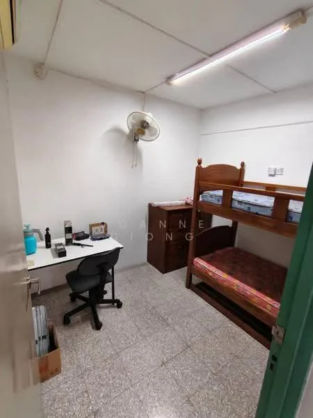 Room features: bunk bed with wooden frame, mattress on top and bottom bunk, wooden dresser, desk with chair, table lamp, wall-mounted ceiling fan, grey tiled flooring, white painted walls, overhead fluorescent lighting; style: minimalist.