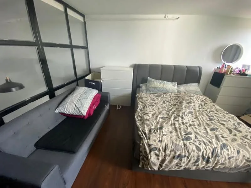 Bedroom features: queen-size bed with upholstered headboard, bedding with patterned duvet cover, nightstand with lamp, white dresser, grey fabric sofa, wood flooring, large round mirror, decorative items on dresser; style: modern.