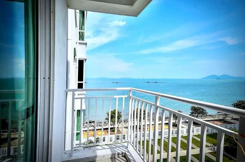 Room features: balcony with white railing, ocean view, clear blue sky, concrete flooring, glass sliding door, white painted walls; style: modern; view: sea.