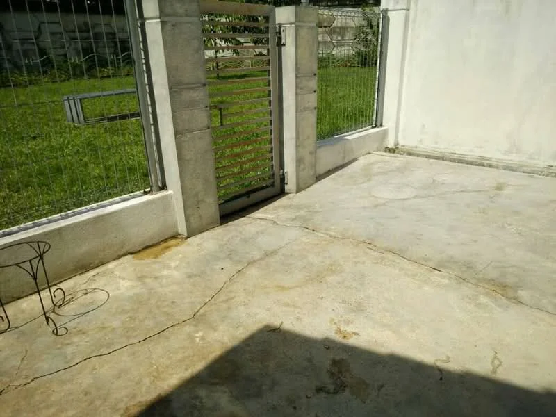 Exterior features: concrete flooring, metal gate, fenced perimeter, grass area, exposed concrete wall; style: minimalist.