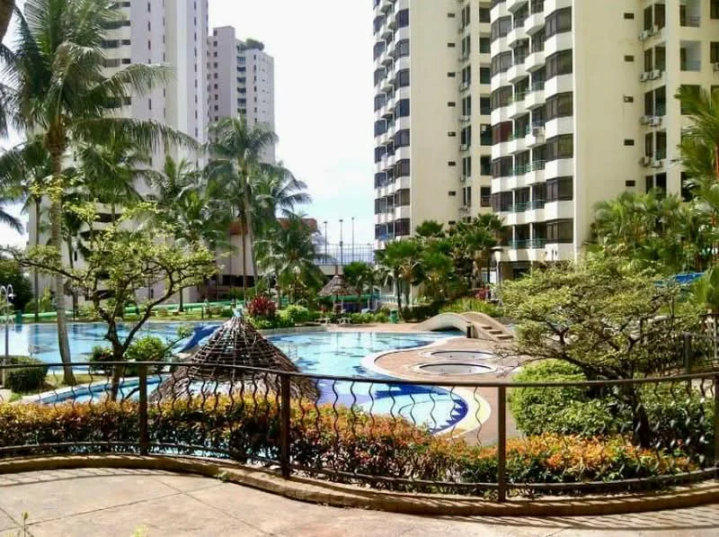 Exterior type: high-rise condominium; features: swimming pool, infinity edge pool, children's playground, landscaped garden, manicured lawn, palm trees, tropical landscaping, pool deck with loungers, jacuzzi, water slide, multiple high-rise buildings, fenced perimeter; style: modern.