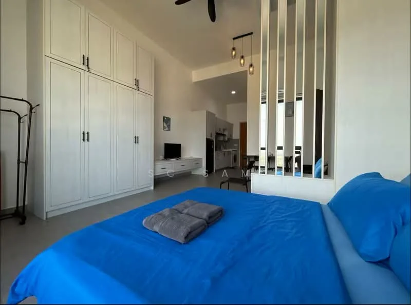 Bedroom features: blue bedding, queen-size bed, upholstered headboard, built-in wardrobe with white doors, ceiling fan with light, floor-to-ceiling windows, grey towels on bed, decorative wall partition, light-colored flooring, wall-mounted TV, open layout to kitchen and dining area; style: modern.