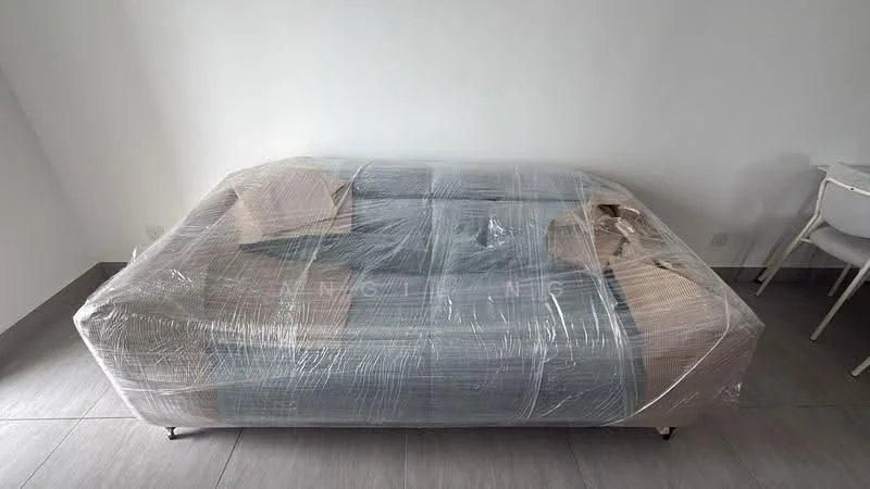 Room features: sofa wrapped in plastic, light grey upholstery, metal legs, neutral wall colour, grey tile flooring, white dining chair visible, minimalist decor; style: modern.