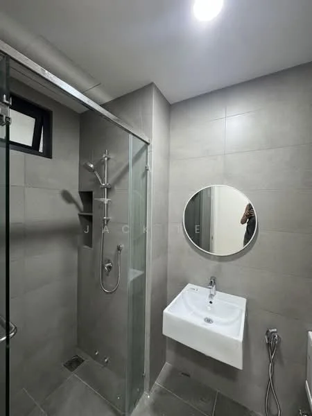 Bathroom features: glass shower enclosure, rain shower head, handheld shower, wall-mounted faucet, round mirror, white wall-mounted sink, grey tiled walls, grey tiled flooring, recessed ceiling lights, window for natural light; style: modern.