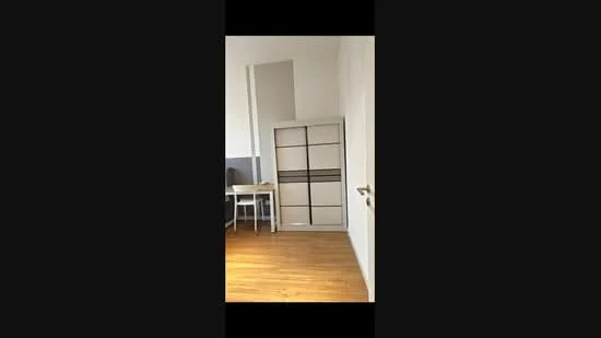 Room features: wooden flooring, white painted walls, built-in wardrobe with sliding doors, desk with chair, natural light from window; style: modern.