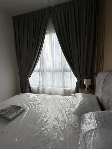 Bedroom features: queen-size bed, upholstered headboard, bedside lamp, floor-to-ceiling window, sheer curtains, dark grey curtains, decorative throw pillows, bed linens, wooden nightstand; style: modern; view: city.