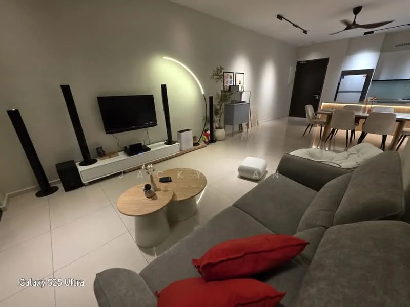 Living features: grey fabric sectional sofa, red decorative cushions, round wooden coffee table, white TV console, wall-mounted TV, black floor speakers, arc floor lamp, recessed ceiling lights, large windows with sheer curtains, dining area visible in background, open-plan layout, light-colored tiled flooring, neutral painted walls; style: modern.