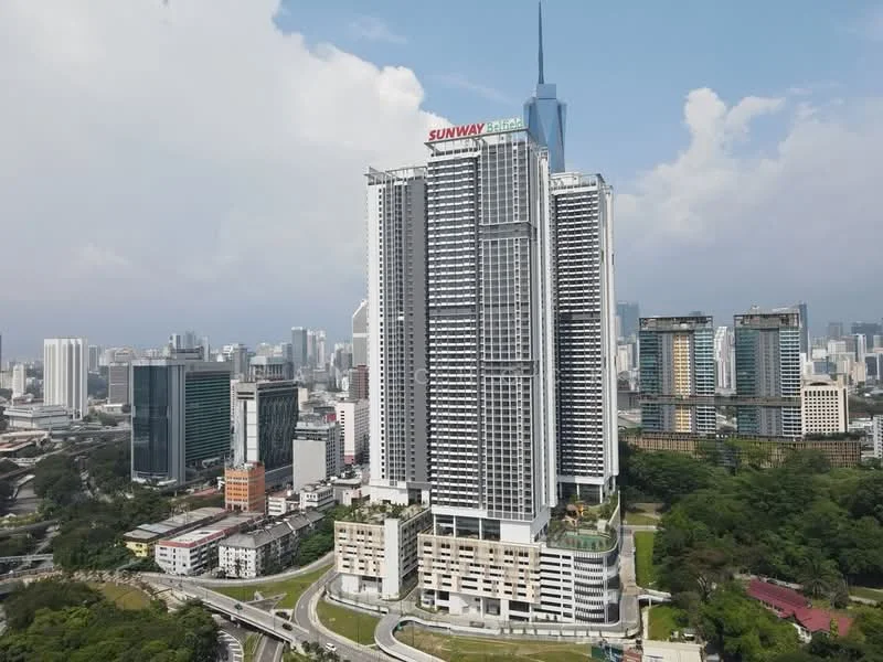 Exterior type: high-rise condominium; features: glass curtain wall, white painted facade, recessed balconies, feature lighting at night, approximately 40-storey high-rise, surrounded by mature greenery, urban context with city skyline in background; style: modern.