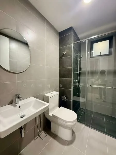 Bathroom features: grey tiled walls, black tiled flooring, round mirror, single-sink vanity with chrome faucet, one-piece toilet, walk-in shower with glass enclosure, rain shower head, handheld shower, shower wall with tile cladding, window for natural light; style: modern.