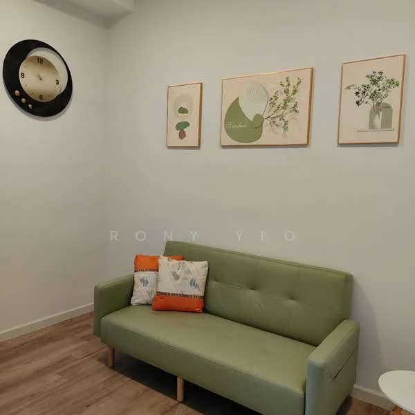 Living features: green fabric sofa, wooden legs on sofa, decorative cushions with patterns, white wall, wooden flooring, framed artwork on walls, round wall clock, small white side table; style: modern.
