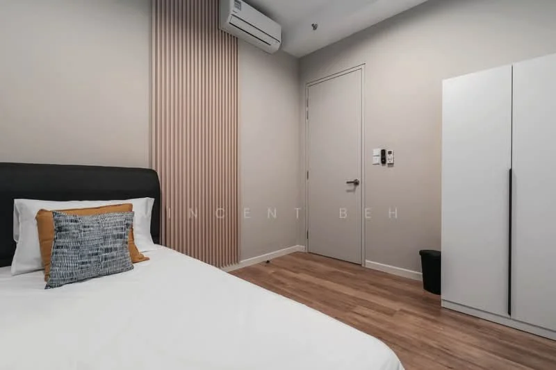 Bedroom features: queen-size bed with black headboard, white bedding, decorative yellow and grey throw pillow, wooden flooring, wall-mounted split AC unit, light grey painted walls, vertical wood panel accent wall, white wardrobe, door with modern handle, wall-mounted intercom panel, waste bin; style: modern.