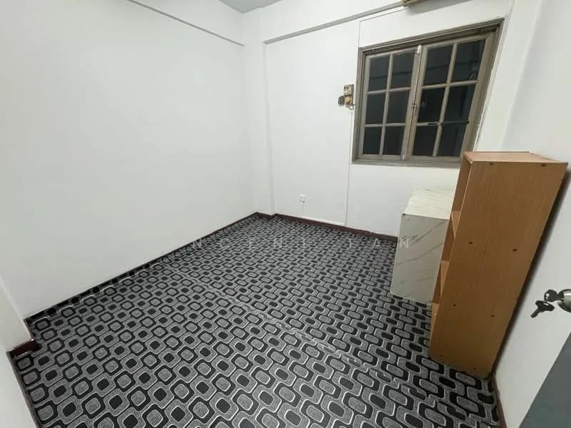 Room features: white painted walls, grey patterned flooring, single window with grid design, wooden cabinet, empty space, no visible furniture, light ceiling, no visible lighting fixtures.