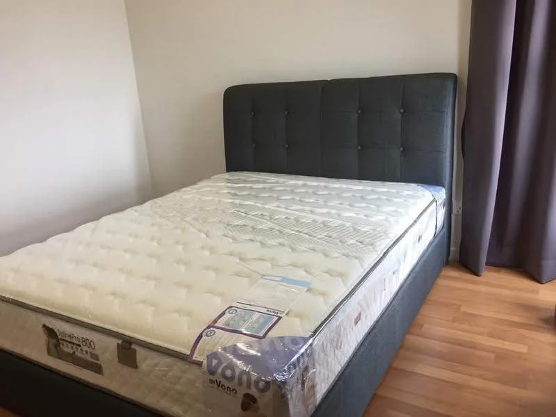 Bedroom features: queen-size bed with upholstered headboard, grey fabric headboard, mattress with protective cover, wooden flooring, light grey walls, floor-to-ceiling window with grey curtains; style: modern.