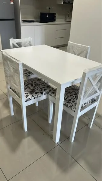 Dining features: white dining table, 4 dining chairs with patterned upholstery, ceramic tile flooring, white cabinetry in background, kitchen appliances visible in background, neutral wall color, natural light from window, decorative table setting; style: modern.