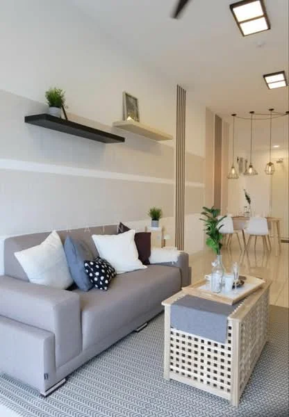 Living features: 3-seater fabric sofa in beige, decorative cushions in various colors, woven coffee table with storage, area rug with geometric pattern, wall-mounted shelves in black and beige, pendant lighting fixtures, recessed ceiling lights, white painted walls, light-colored flooring, indoor plant; style: modern.