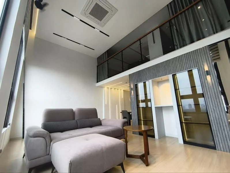 Living features: grey fabric sofa, ottoman, wooden flooring, recessed downlights, exposed ceiling beams, floor-to-ceiling windows, balcony with glass railing, open-plan layout, modern decor, air conditioning unit; style: modern; view: city.