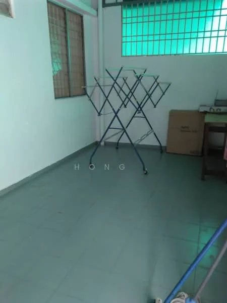 Room features: green tiled flooring, white painted walls, large windows with green glass panes, clothes drying rack, cardboard box, wooden table, minimal furniture; style: minimalist.