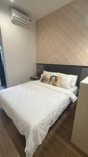 Bedroom features: queen-size bed with white bedding, upholstered headboard, wooden bedside table, decorative throw pillows with leaf pattern, wall-mounted air conditioning unit, light wood accent wall, laminate flooring, built-in wardrobe; style: modern.